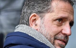 Fabio Paratici in primo piano, possibile nuovo Direttore Sportivo del Milan, con lo sfondo dello stadio San Siro e il logo del club rossonero.